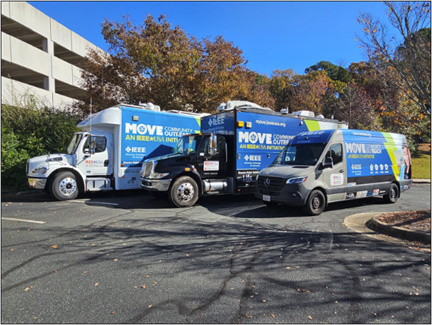Three IEEE MOVE Community Outreach trucks parked in a parking lot.