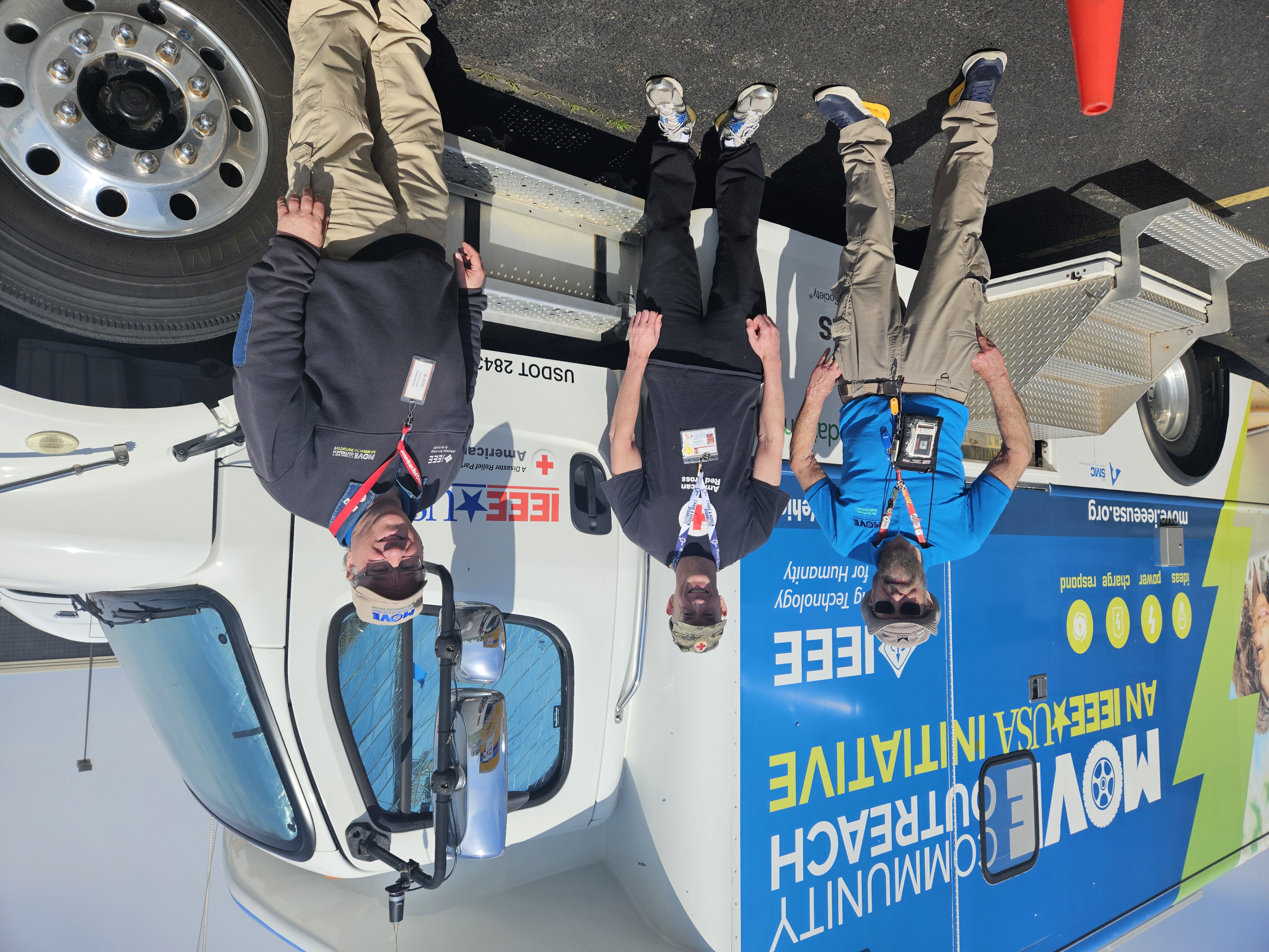 Three volunteers from the Institute of Electrical and Electronics Engineers (IEEE) pose by their disaster relief truck.